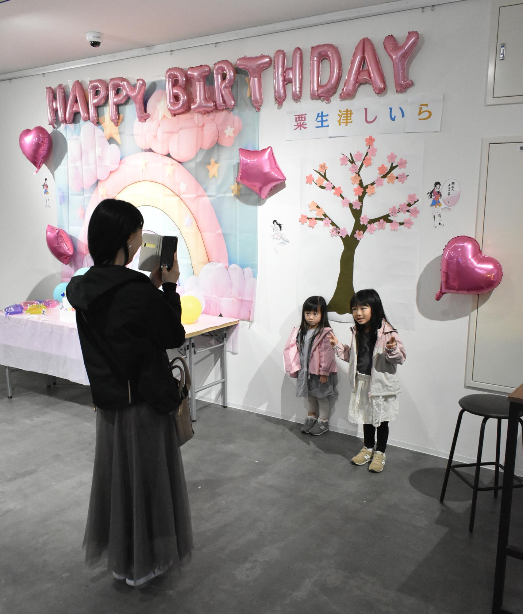 お祝いメッセージの前で写真を撮る親子