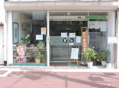 内外に植え込みを置いたガラス張りのエントランスの地域活動支援センターNPO法人リカバリー燕、Cafeさんぽ道の外観写真