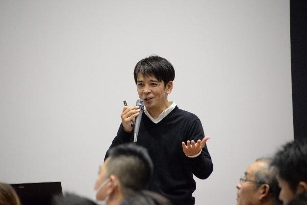 大勢の高齢者の前で講演している新潟市障がい者あぐりサポートセンター担当者の写真