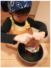 女の子が鍋になめこを入れている写真