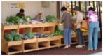 商店の前に陳列された野菜を見ている人たちの写真