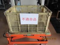 赤い荷台に黄色い箱が置いてあって不適合品と書かれた札が貼ってある写真