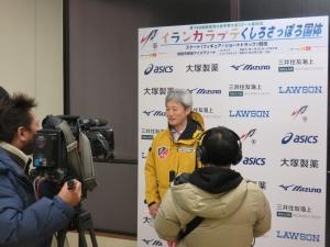 カメラマンたちの前で話をする男性の写真