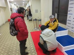 廊下で取材を受ける男性の写真