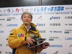 スケート靴を持って微笑む男性の写真