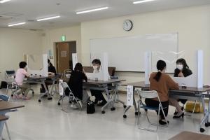 アクリル板で仕切られた机で1対1で向かい合って面談している写真
