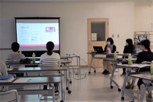 プロジェクターに映像が投影され、それを見ている人々の写真