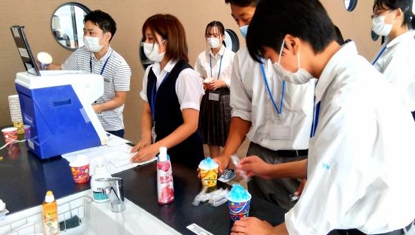 ネームタグをつけ、かき氷を作っている生徒と社員の写真