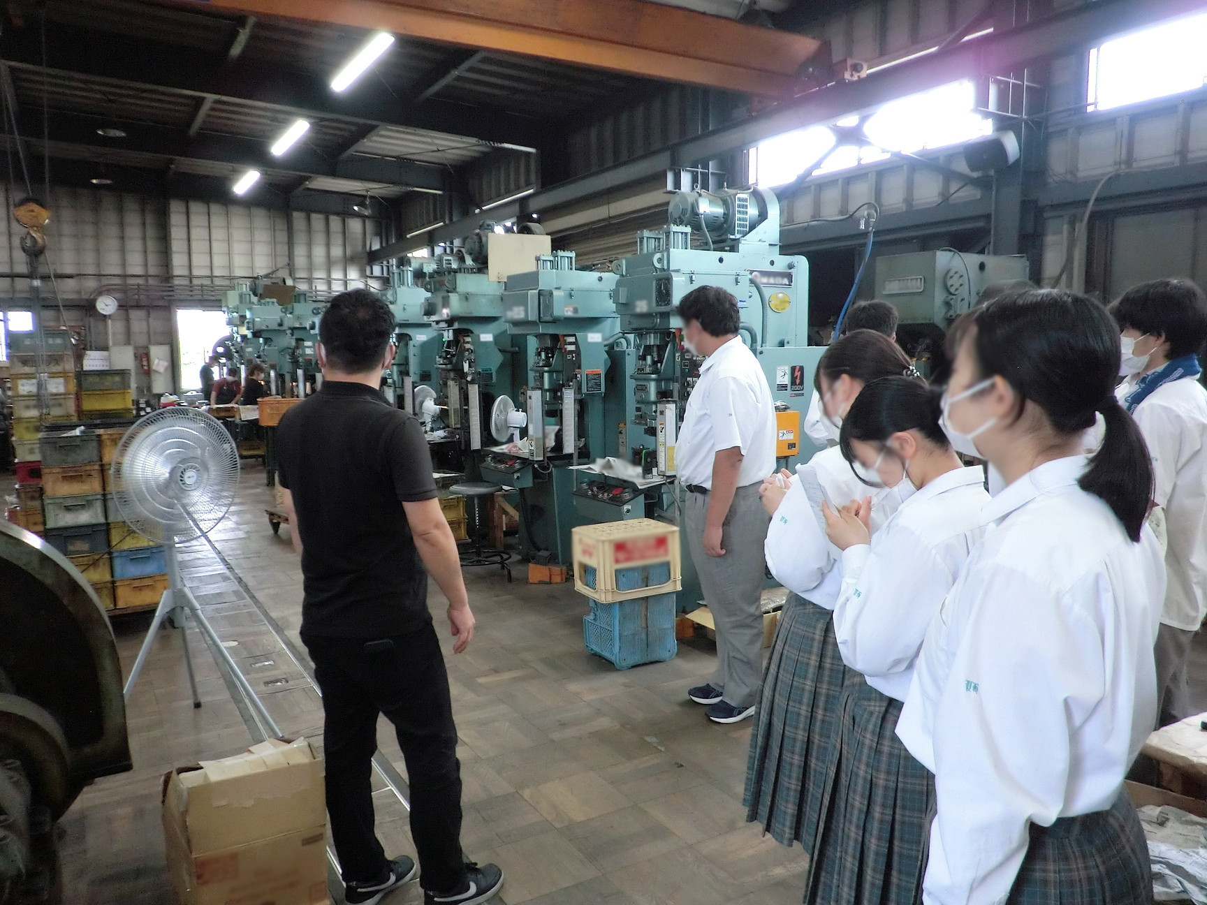 社員が生徒に対して、製造現場の設備の説明をしているところ
