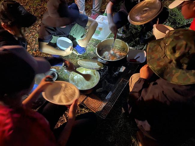 サバイバルキャンプで真夜中の食事をする塾生たち