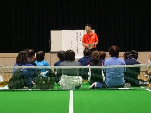 体育館で講師に説明を受ける参加者たちの写真