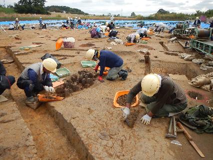 遺跡の上で、しゃがみこんで発掘調査をしている人たちの写真