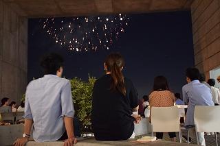 夜空に打ちあがる花火を眺めている男女の写真