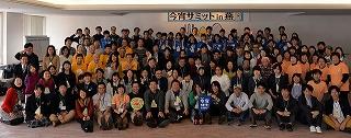 今宵サミットイン燕と書かれた横断幕の下で並んで記念撮影をしている人たちの写真