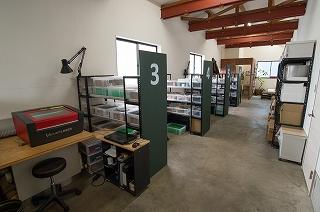 番号が振られた棚と作業台のある工房の写真