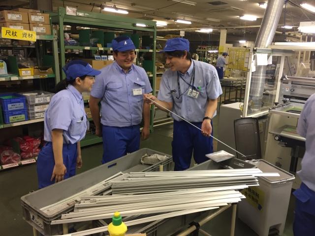 制服を着て、部品を眺めながら作業をする人たちの写真