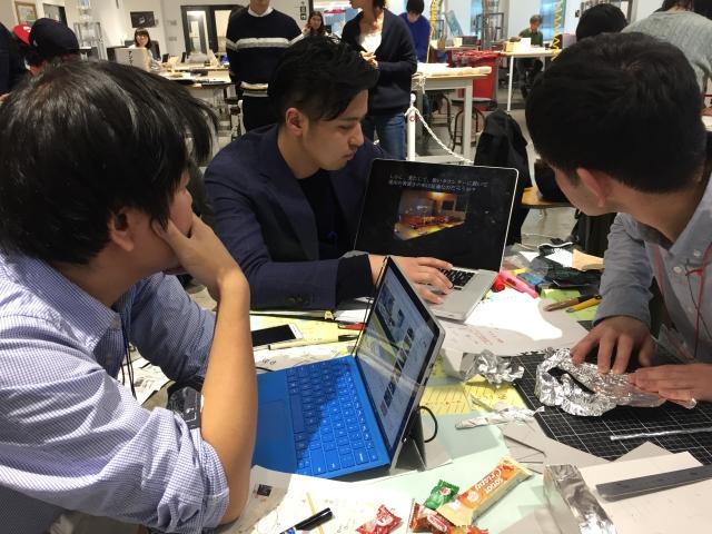 ノートPCの画面を見せ合いながら話をする人たちの写真