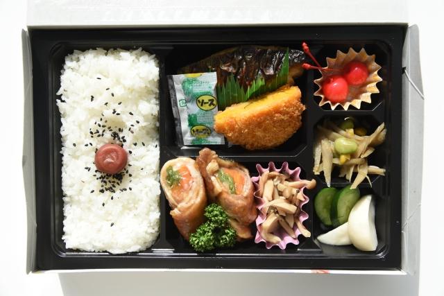 コロッケ、焼き魚などが入ったお弁当の写真