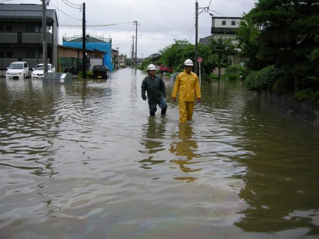 浸水した街を歩く2名の男性の写真