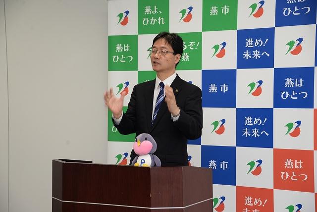 身振りを交えて話すスーツ姿の市長の写真