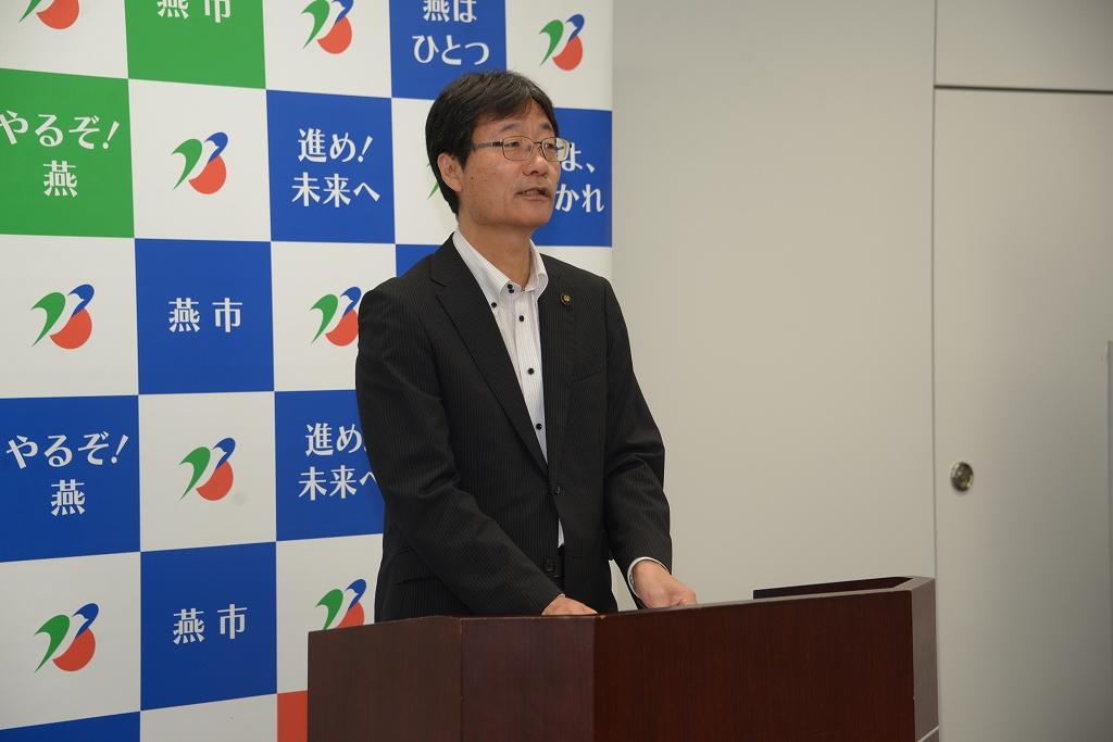 スーツ姿の市長が演台で話している写真