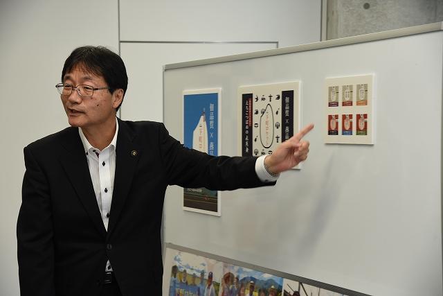 ホワイトボードの掲示物を指さしながら話す市長の写真