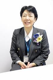 スーツ姿でカメラに向かって笑顔を見せる横澤富士子さんの写真