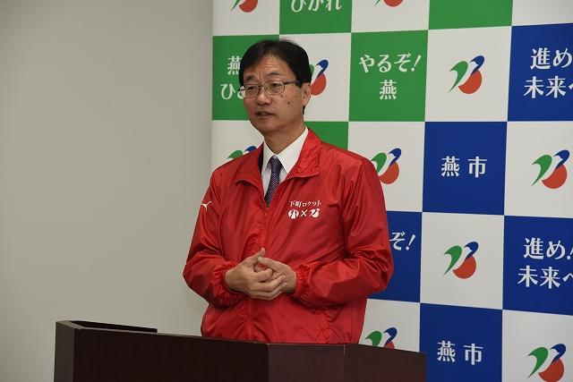 両手を体の前で組み、演台で話をする市長の写真