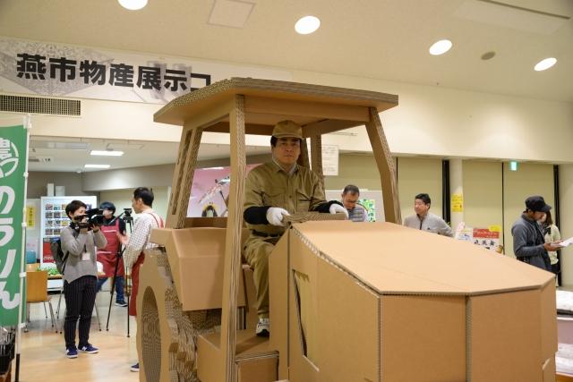 ダンボール製のトラクターに乗っている男性の写真