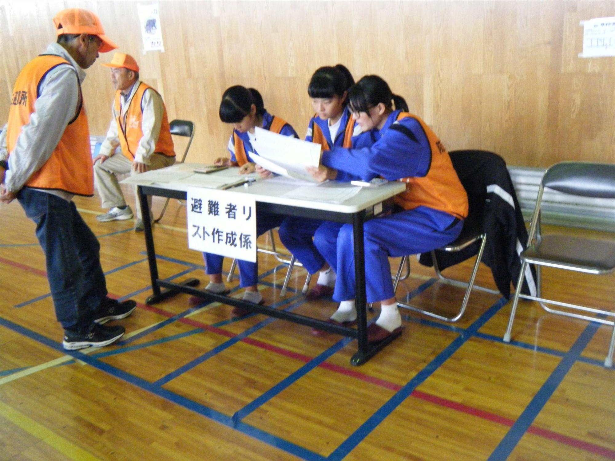 体育館で受付をする児童たちの写真