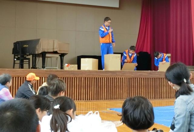 体育館に児童たちと保護者が集まっている写真