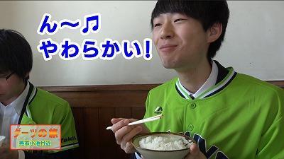 黄緑色のユニフォームを着た男子学生がご飯を食べている写真