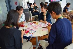 円形のテーブルを囲んで話し合う人たちの写真