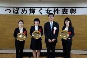 スーツ姿の女性たちが市長と並んで記念撮影をしている写真
