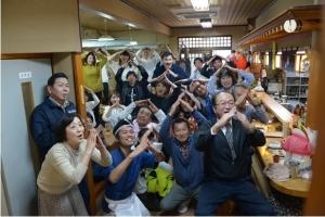 食事処でポーズをとり記念撮影する人たちの写真
