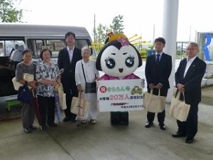 バスの前でゆるキャラと一緒に記念撮影する人たちの写真