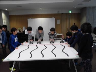 児童たちが一列に並んでロボットを走らせようとしている写真