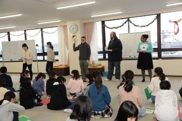 教室で講師たちが児童たちに向かって話している写真