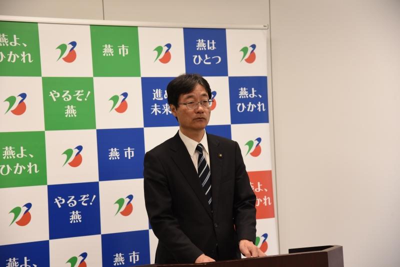 スーツ姿で演台に立つ市長の写真