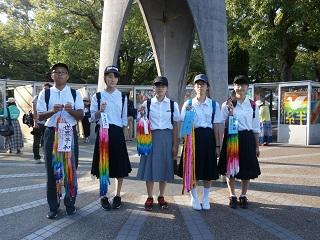 千羽鶴を手に持ちオブジェの前で記念撮影する児童たちの写真