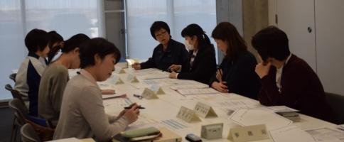 資料を見ながら会議をしている女性たちの写真