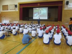 体育館で赤白帽子を被って座る児童たちの写真