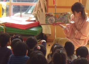 子供たちに絵本を読み聞かせている女性の写真