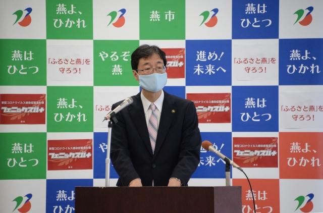 マスクをして演台に立つスーツ姿の市長の写真