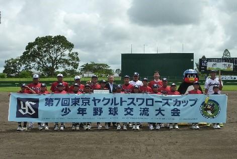 「第7回ヤクルトスワローズカップ 少年野球交流大会」の横断幕を持つ野球チームの子供たちの集合写真