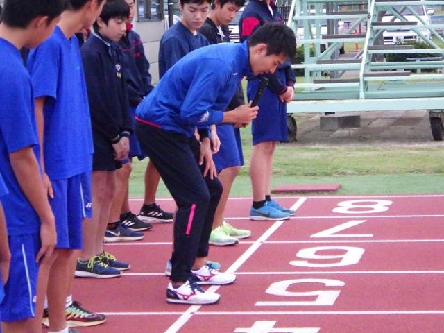 青いユニフォームを着た生徒たちが徒競走レーンに並んで立っている写真