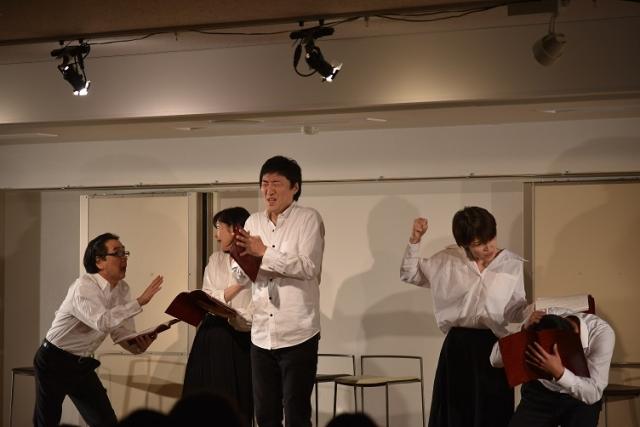白いシャツと黒いボトムを履いた男女5名が表情豊かに演技をしている写真