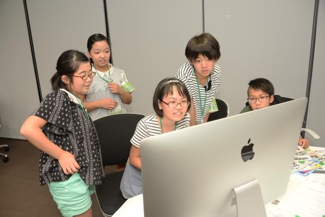 5人の児童たちがパソコンのモニターを覗き込んでいる写真