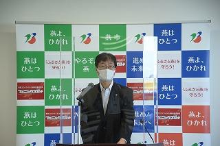 マスクをして透明のシールドに囲まれながら会見をする市長の写真