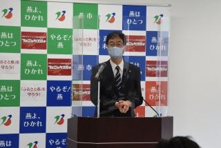 マスクをして透明のシールドに囲まれながら会見をする市長の写真